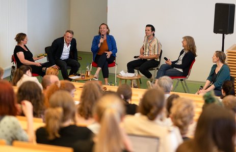 Menschen sitzen im Audimax der Hochschule Coburg und schauen nach vorne zur Podiumsdiskussion..