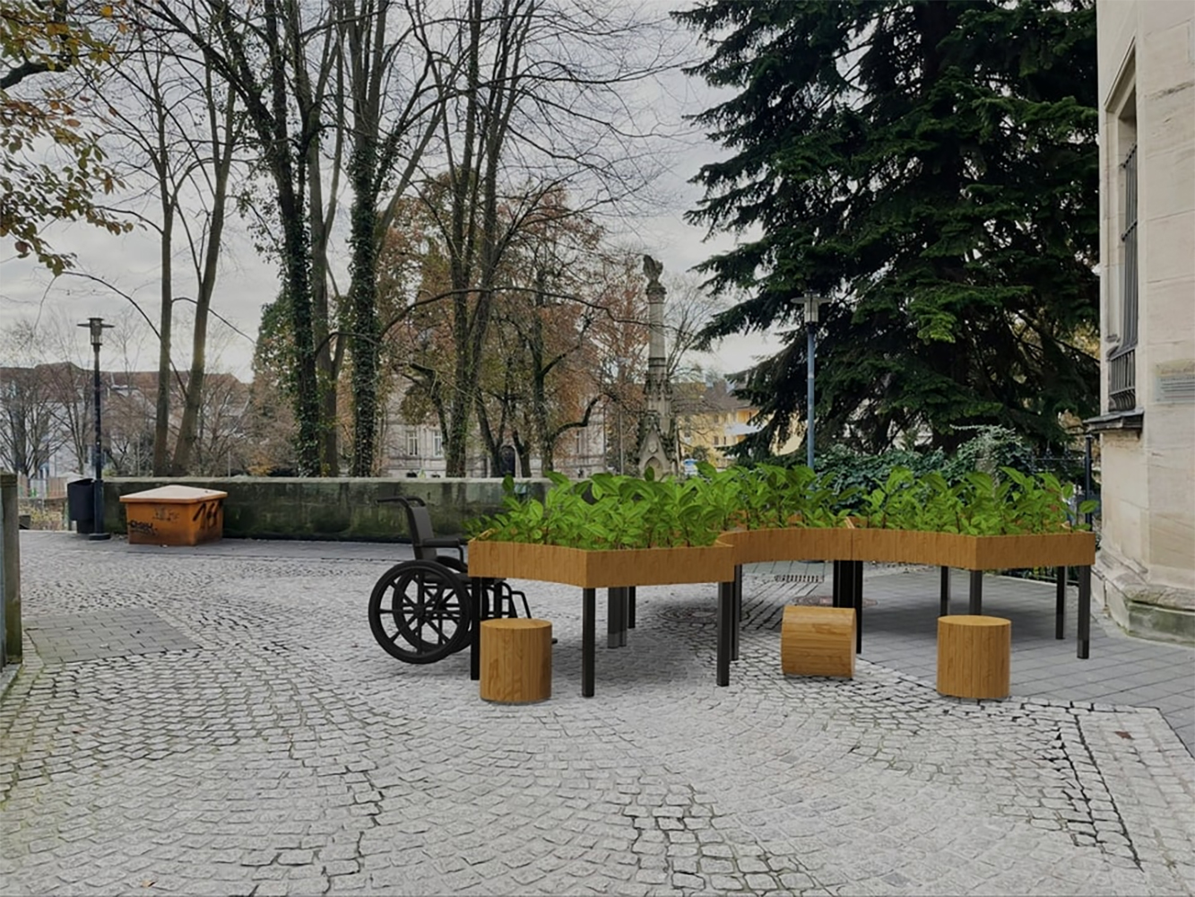 Ein rollstuhlgerechtes Hochbeet mit üppigen grünen Pflanzen steht auf einem Kopfsteinpflasterweg an der Hochschule Coburg. In der Nähe ergänzen Holzhocker die blattlosen Bäume und das immergrüne Laub im Hintergrund und schaffen eine ruhige Außenumgebung.