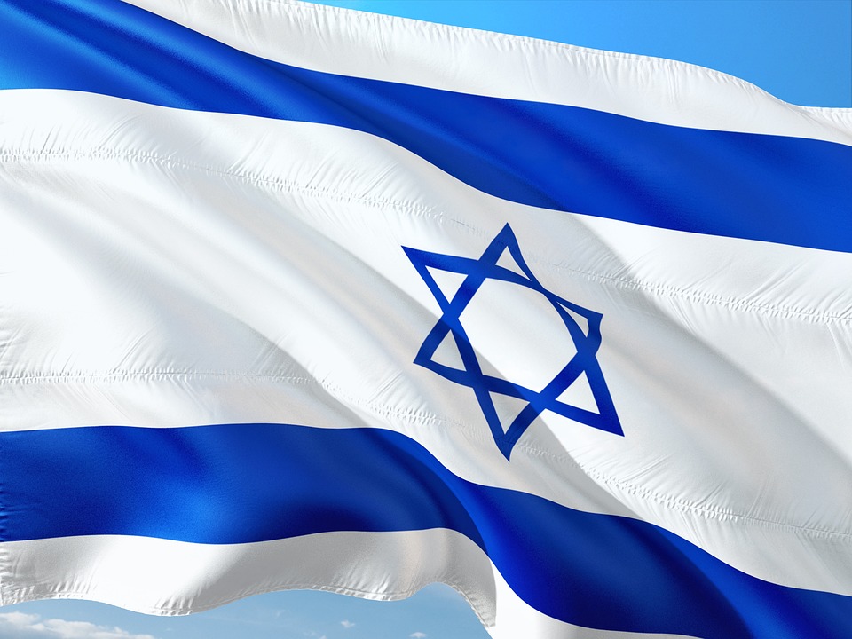 Das Bild zeigt die Nationalflagge Israels, die vor einem klaren blauen Himmel im Wind weht und an die lebendige Stimmung erinnert, die oft bei internationalen Zusammenkünften wie denen an der Hochschule Coburg gefeiert wird. Die Flagge zeigt zwei horizontale blaue Streifen und einen zentralen blauen Davidstern auf weißem Hintergrund.