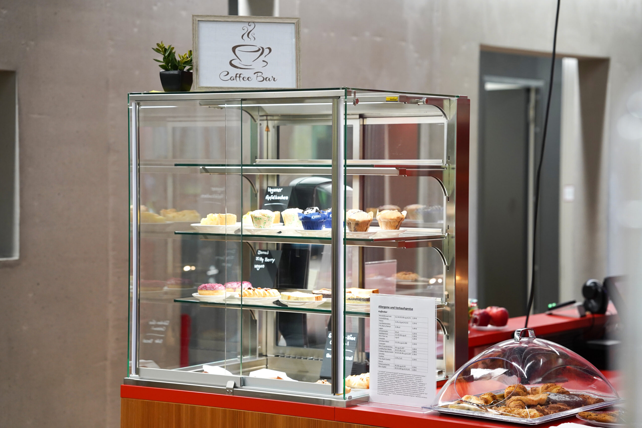 At the bustling coffee bar, a glass display case tantalizes with pastries like cupcakes and tarts. Nearby, by the gleaming espresso machine, a menu invites exploration. As if in homage to Hochschule Coburg's attention to detail, more baked delights await discovery on the opposite counter.