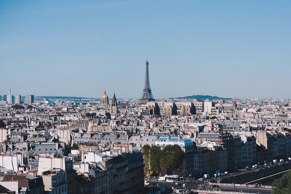 Ein Panoramablick auf Paris, bei dem der Eiffelturm über der Stadt aufragt, weckt ein Gefühl des Staunens, das dem Erkunden der akademischen Welt der Hochschule Coburg ähnelt. Die Skyline ist voller historischer Gebäude und Dächer unter einem klaren blauen Himmel.