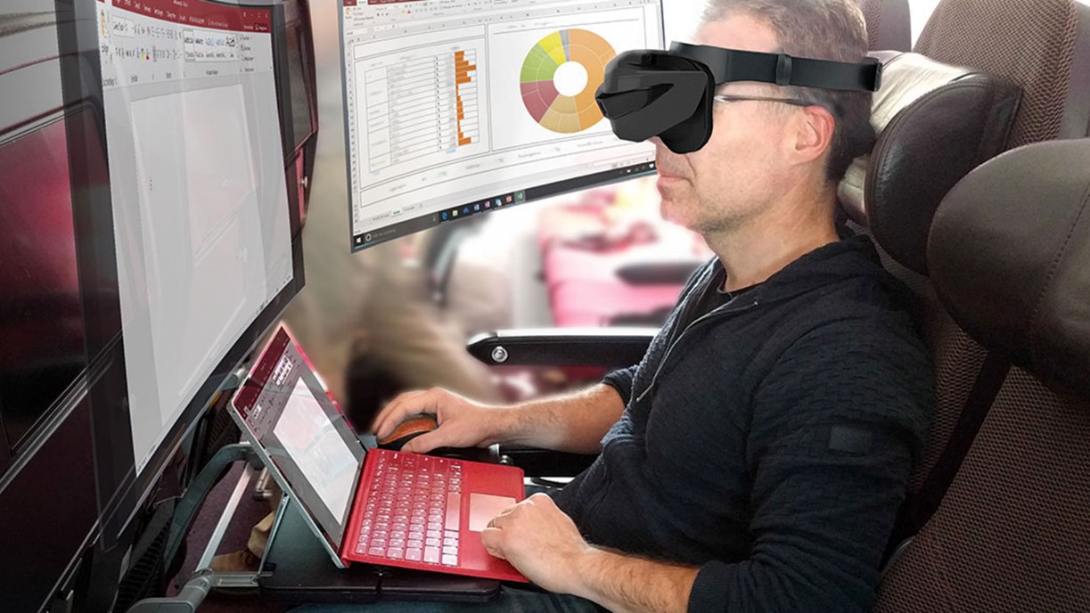 Eine Person mit VR-Brille sitzt auf einem Stuhl, nutzt mehrere Computerbildschirme und tippt auf einem roten Laptop, was an die hochmodernen Technologielabore der Hochschule Coburg erinnert. Auf den Bildschirmen werden Diagramme und ein Dokument angezeigt, was Multitasking oder die Arbeit in einer dynamischen digitalen Umgebung suggeriert.