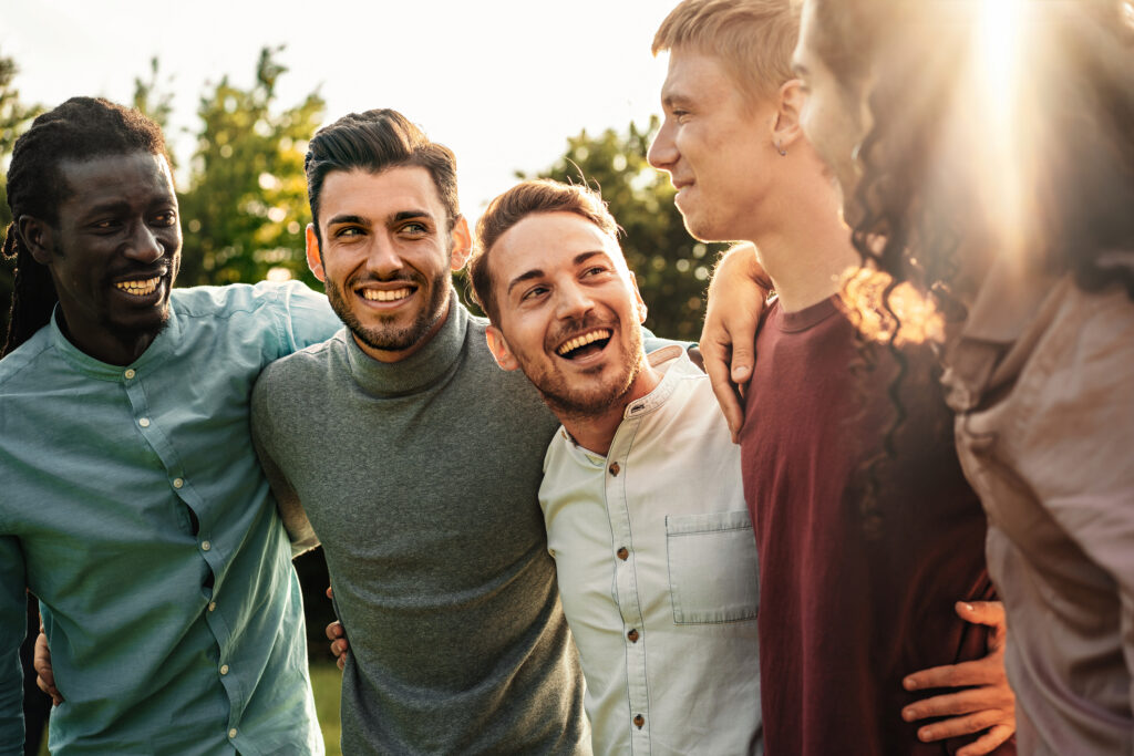 A group of joyful male friends bonding and laughing together in an outdoor setting, radiating friendship and happiness.